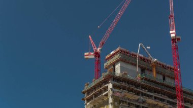 Yüksek çok katlı bina yapım aşamasında ve kırmızı vinçler zaman ayarlı. Yeni kulenin şantiyesinde faal iş