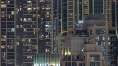 Modern konut binalarındaki büyük parlayan pencereler geceleri zaman ayarlı, sıra sıra parlıyor. Aydınlatılmış gökdelen