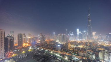 Dubai Şehir Merkezi 'nden gece gündüz geçiş zamanı güneş en yüksek gökdelenden ve güneş doğarken tepeden uzun gölgeli diğer kulelerden yansıyor. Birleşik Arap Emirlikleri. Eski şehrin geleneksel evleri