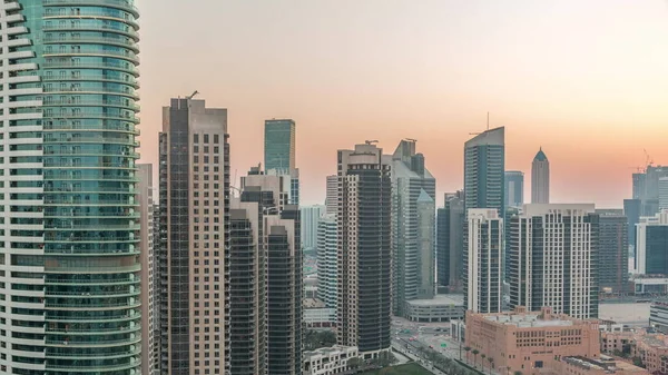 在迪拜 商业中心的塔楼从天到晚都在过渡 日落后一些摩天大楼和在建的新建筑物的屋顶视图 灯亮着 — 图库照片
