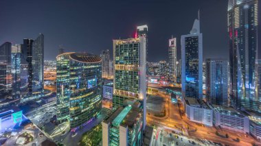 Dubai Uluslararası Finans Merkezi Gökdelenleri Hava Gecesi Zamanlaması. Karayolu üzerinde trafik olan aydınlık kuleler yukarıdan ultra geniş açı görüntüsü