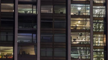 Modern ofisteki büyük parlayan pencereler ve konut binaları gece saatlerine göre ayarlanıyor, pencereler ışık saçıyor. Evde çalışma yeri