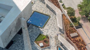 DIFC bölgesindeki Cami 'nin dış cephesi tüm gün boyunca yukarıdan gölgelerin hızla hareket etmesiyle korunuyor. Ağaçlar ve yeşil çimlerle dolu kapı bulvarında gezinti