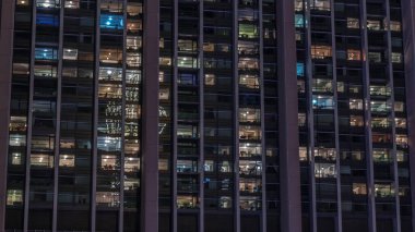 Modern ofisteki büyük parlayan pencereler ve konut binaları gece saatlerine göre ayarlanıyor, pencereler ışık saçıyor. Birçok apartman bloğu