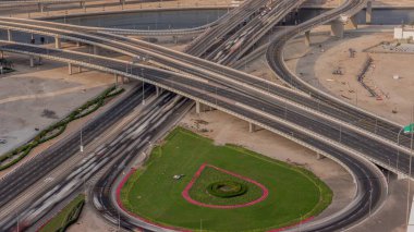 Business Bay Timelapse 'ın kavşağındaki şehir trafiği. Yukarıdan yol kavşağının havadan görünüşü, otomobil trafiği ve birçok arabanın sıkışıklığı. Yeşil çimenli döngü