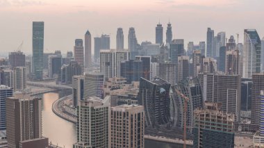 Dubai iş sahası kulelerinin modern mimarisine sahip Skyline 'dan geceye geçiş zamanı. Gün batımından sonra kanal ve şantiyeli hava manzarası