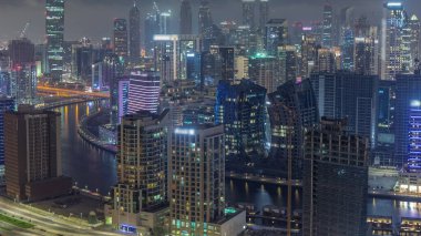 Dubai 'nin modern mimarisine sahip Skyline gece kuleleri aydınlatıyordu. Kanal ve şantiyeli hava manzarası