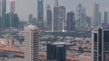 Dubai 'nin finans bölgesindeki gökdelenler gündüzden geceye geçiş zamanı. Business Bay bölgesinden birçok kuleye panoramik manzara