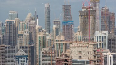 İnşaat halindeki çok katlı binalar ve birçok vinç zaman ayarlı. Çevredeki yeni kulelerin ve gökdelenlerin inşaatında aktif iş. Mavi bulutlu gökyüzü