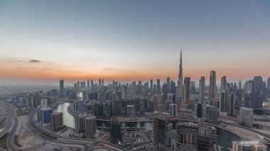 Dubai iş sahası ve şehir merkezindeki kulelerin modern mimarisi ile panoramik ufuk çizgisi günden geceye geçiş zamanı. Gün batımından sonra kanal ve şantiyeli hava manzarası
