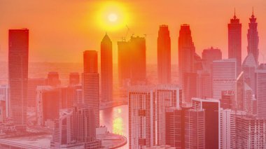 Günbatımında Dubai iş alanı kulelerinin modern mimarisi ile Skyline. Kanal ve şantiyeli hava manzarası. Turuncu gökyüzü