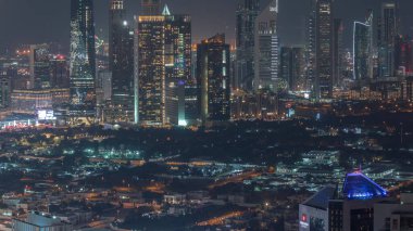 Dubai 'nin finans bölgesindeki gökdelenlerin sıraları gece uçuşları. Business Bay bölgesinden birçok ışıklandırılmış kule ve villa için panoramik manzara