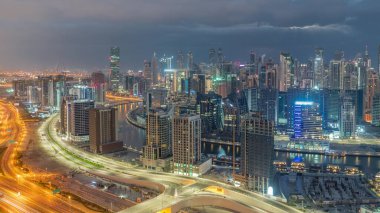 Dubai 'nin modern mimarisine sahip Skyline, gece gündüz geçiş zamanı kulelerini aydınlattı. Güneş doğmadan önce kanal ve şantiyeli havadan panoramik görüntü