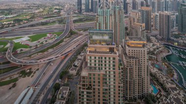 Dubai marinası ve JLT gökdelenleri Sheikh Zayed Yolu boyunca günden geceye geçiş zamanı. İkamet yeri ve ofis binaları yukarıdan büyük bir kavşağa sahip.