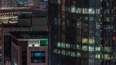 Dubai Internet City Gölü 'nün havadan görünüşü. Ofis kulesinde gece vakti parlayan pencereler var. Yukarıdan. Aydınlatılmış binalar çatılar