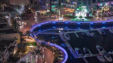 Dubai Marina rıhtımında, avuçlarında avuçlar, gece uçuşu zamanlaması, Dubai, BAE. Birçok restoran ve yüzen yatlar