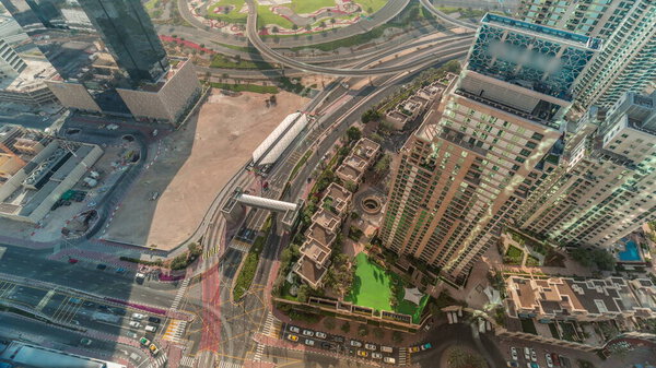 Aerial look down view of a road intersection between skyscrapers in the city during all day timelapse with shadows moving fast. Urban landscape of Dubai Marina district in UAE with cars and tram