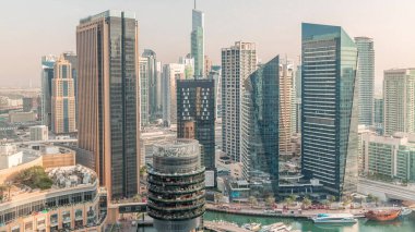 Dubai Marina Skyline 'ın arka planında JLT gökdelenleri var. Cam yüzeyi olan kuleler ve gün batımında yatları olan rıhtım.