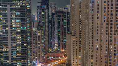JBR ve Dubai Marina gökdelenlerinin gökdelenlerinin gökdelenlerinin parlayan pencereleriyle deniz kıyısında yaşayan apartmanların hava sahasının gece zaman çizelgesine bakın. Yol kavşağında trafik ve yaya geçidi