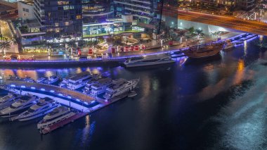 Dubai marinası rıhtımda gece vakti hava kanalı boyunca gezinti yaptı. Dubai 'de yüzen yatları ve tekneleri olan modern yerleşim yerleri.