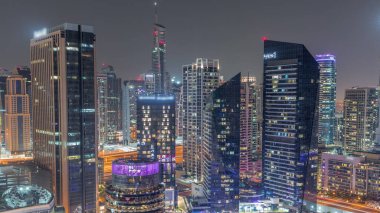 Dubai Marina Skyline ve JLT gökdelenleri tüm gece boyunca arka plan anteninde. Cam yüzeyi ve ışıkları sönen aydınlık kuleler.