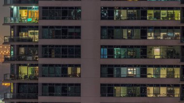 Modern apartmanlardaki pencere ışıkları geceleri zaman ayarlı. İçinde aydınlık odalar olan çok katlı gökdelenler.