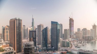 Dubai yat limanına ve kanalın etrafındaki gökdelenlere yüzen teknelerin zaman ayarlı görüntüsü. Yat kulübünde beyaz tekneler var.