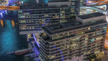 JBR ve Dubai Marina 'ya genel bakış. Rıhtımda yaşayan apartmanlardaki modern binaların gökyüzü. Gece saatleri. Sudaki tekneler ve pencerelerdeki akşam ışıkları