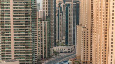 JBR ve Dubai Marina gökdelenleri, deniz kenarındaki gökdelenler, havadan izlenen daireler. Gün doğarken kavşakta trafik ve yaya köprüsü.