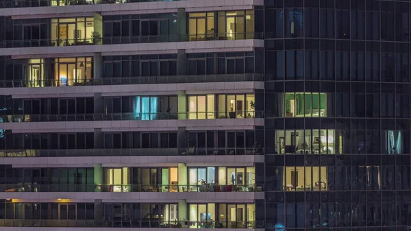 Modern ofisteki pencere ışıkları ve geceleri konut binaları. İçinde aydınlık daireler olan çok katlı gökdelenler.