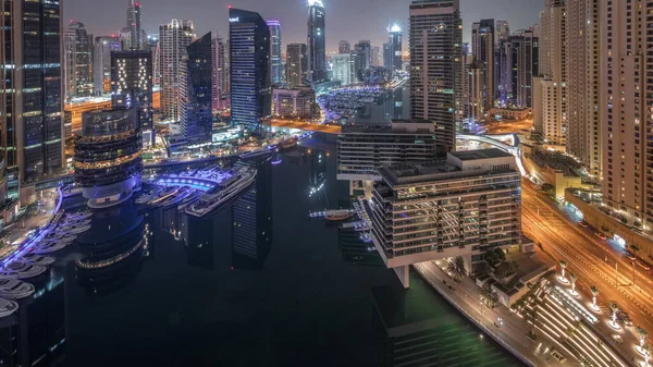 从空中俯瞰迪拜码头 环绕着运河的摩天大楼闪烁着明晃晃的光芒 游艇夜以继日地飞驰而过 白船在日出前停泊在游艇俱乐部 — 图库照片