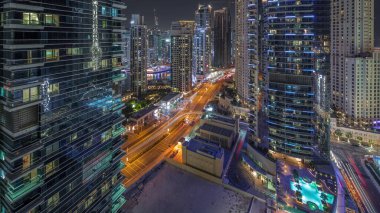 Dubai Marina ve JBR bölgesinin manzarası ve aydınlık gökdelenlerle dolu gece hava trafiği.