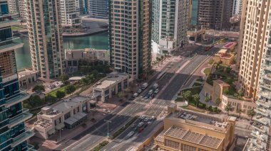 Dubai Marina gökdelenlerindeki hava manzarası ve kanal zamanındaki yat. Yol boyunca kuleler ve sahil şeridi yakınında trafik. Dubai, Birleşik Arap Emirlikleri