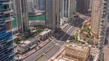 Dubai Marina gökdelenlerindeki hava manzarası ve yol üzerindeki trafik tüm gün boyunca gölgeler hızla ilerledi. Rıhtımdaki yürüme alanı boyunca kuleler. Dubai, Birleşik Arap Emirlikleri