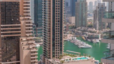 Dubai Marina gökdelenlerindeki hava manzarası ve liman zamanındaki en lüks yat. Yüzme havuzlu bir rıhtım üzerinde yürüme alanı boyunca kuleler. Dubai, Birleşik Arap Emirlikleri