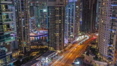 Dubai Marina 'daki hava manzarası tüm gece boyunca gökdelenleri ve yol trafiğini aydınlattı. Rıhtımdaki yürüme alanı boyunca kuleler. Işıklar kapanıyor. Dubai, Birleşik Arap Emirlikleri
