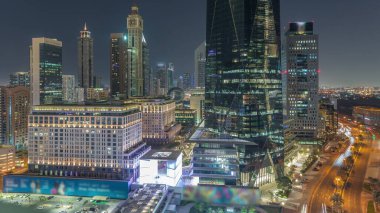 Dubai Uluslararası Finans Bölgesi Gece Zaman Çizelgesi. İş yeri kulelerinin havadan görüntüsü. Şehir merkezine yakın oteller ve alışveriş merkezleriyle aydınlatılmış gökdelenler.