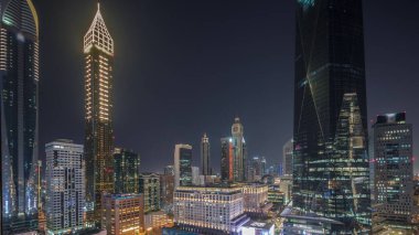 Dubai Uluslararası Finans Bölgesi Gece Zaman Çizelgesi. İş yeri kulelerinin panoramik hava görüntüsü. Karanlık gökdelenlerle aydınlatılmış gökdelenler