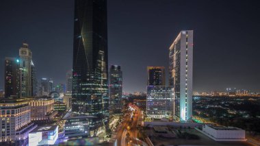 Dubai Uluslararası Finans Bölgesi Gece Zaman Çizelgesi. İş yeri kulelerinin panoramik hava görüntüsü. Aydınlatılmış gökdelenler oteller ve karanlık gökyüzü