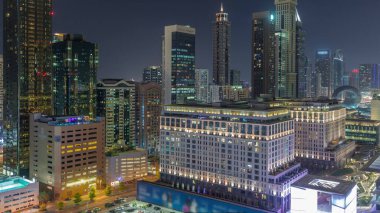 Dubai Uluslararası Finans Bölgesi Gece Zaman Çizelgesi. İş yeri kulelerinin havadan görüntüsü. Şehir merkezine yakın oteller ve alışveriş merkezleriyle aydınlatılmış gökdelenler.