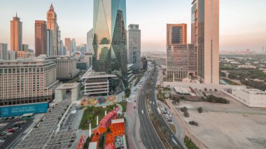 Dubai Uluslararası Finans Bölgesi 'nden gece gündüz trafiğe geçiş zamanı. Gün batımından sonra panoramik ofis kulesi manzarası. Şehir merkezine yakın otelleri ve alışveriş merkezleri olan gökdelenler.