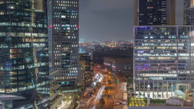 Dubai Uluslararası Finans Bölgesi Gece Zaman Çizelgesi. Yol trafiği ve Deira bölgesinin arka planında iş merkezlerinin hava görüntüsü. Şehir merkezine yakın aydınlık gökdelenler.