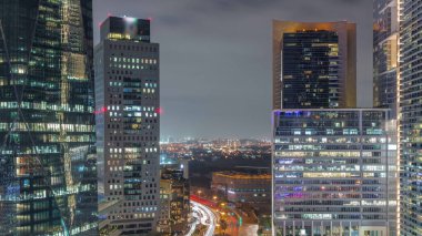 Tüm gece boyunca Dubai Uluslararası Finans Bölgesi. Yol trafiği ve Deira bölgesinin arka planında iş merkezlerinin hava görüntüsü. Aydınlatılmış gökdelenler ve şehir merkezinde ışıklar sönüyor.