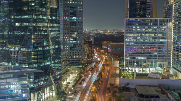 Traffic on a road in Dubai International Financial district night timelapse. Aerial view of business office towers. Illuminated skyscrapers with hotels and shopping malls near downtown