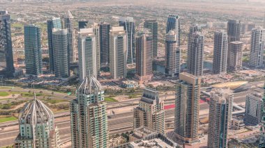 Dubai marina kuleleri ve JLT bölgesi. Şeyh Zayed yolu üzerinde metro istasyonunun yakınındaki trafik. Gölgeler hızla ilerliyor. Yukarıdan aşağıya bak, gökdelenler çatılar, Birleşik Arap Emirlikleri.
