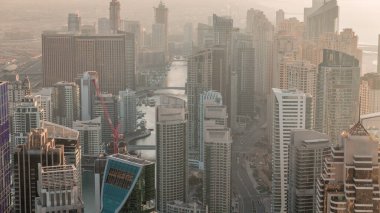 Gökdelenlerle çevrili Dubai Marina 'nın gökdelenlerle çevrili gökdelenler tarafından gün batımından önceki puslu bir akşamda gökyüzü panoramik görüntüsü. Yüzen yatlar ve tekneler. Dubai, BAE