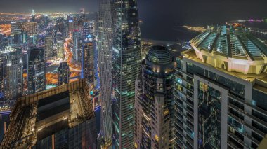 Yukarıdan JBR ve Dubai Marina gökdelenleri ve lüks binaların hava görüntüsü. Aydınlatılmış kuleler çatılar ve yol trafiği