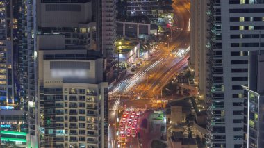 Yukarıdan JBR ve Dubai Marina gökdelenleri ve lüks binaların hava görüntüsü. Aydınlatılmış kuleler ve kavşakta trafik