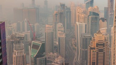 Dubai Marina puslu sabahının Skyline panoramik görüntüsü kıyı şeridi boyunca gökdelenlerle çevrili yapay bir kanalı gösteriyor. Güneş doğmadan önce yüzen yatlar ve tekneler. Dubai, BAE