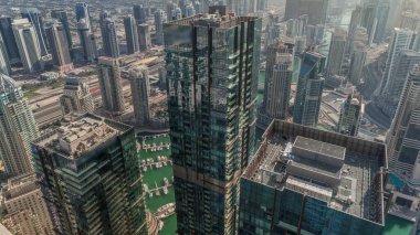 Dubai Marina ve JLT semtleri gökdelenler arasında karayolu trafiği olan panoramik zaman dilimi. Modern kuleler ve gölgeli inşaat alanı akşama kadar hızla ilerliyor.